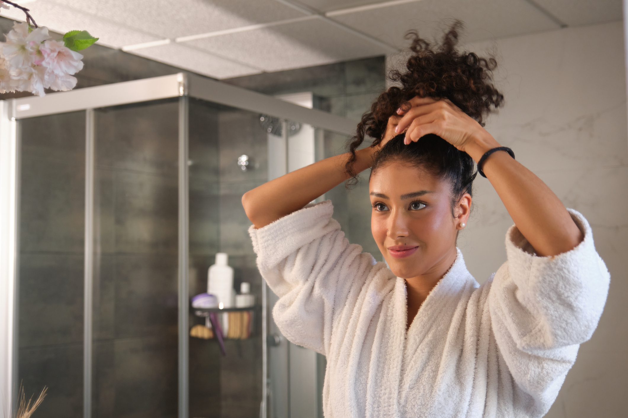 Young woman tying her hair in a modern bathroom