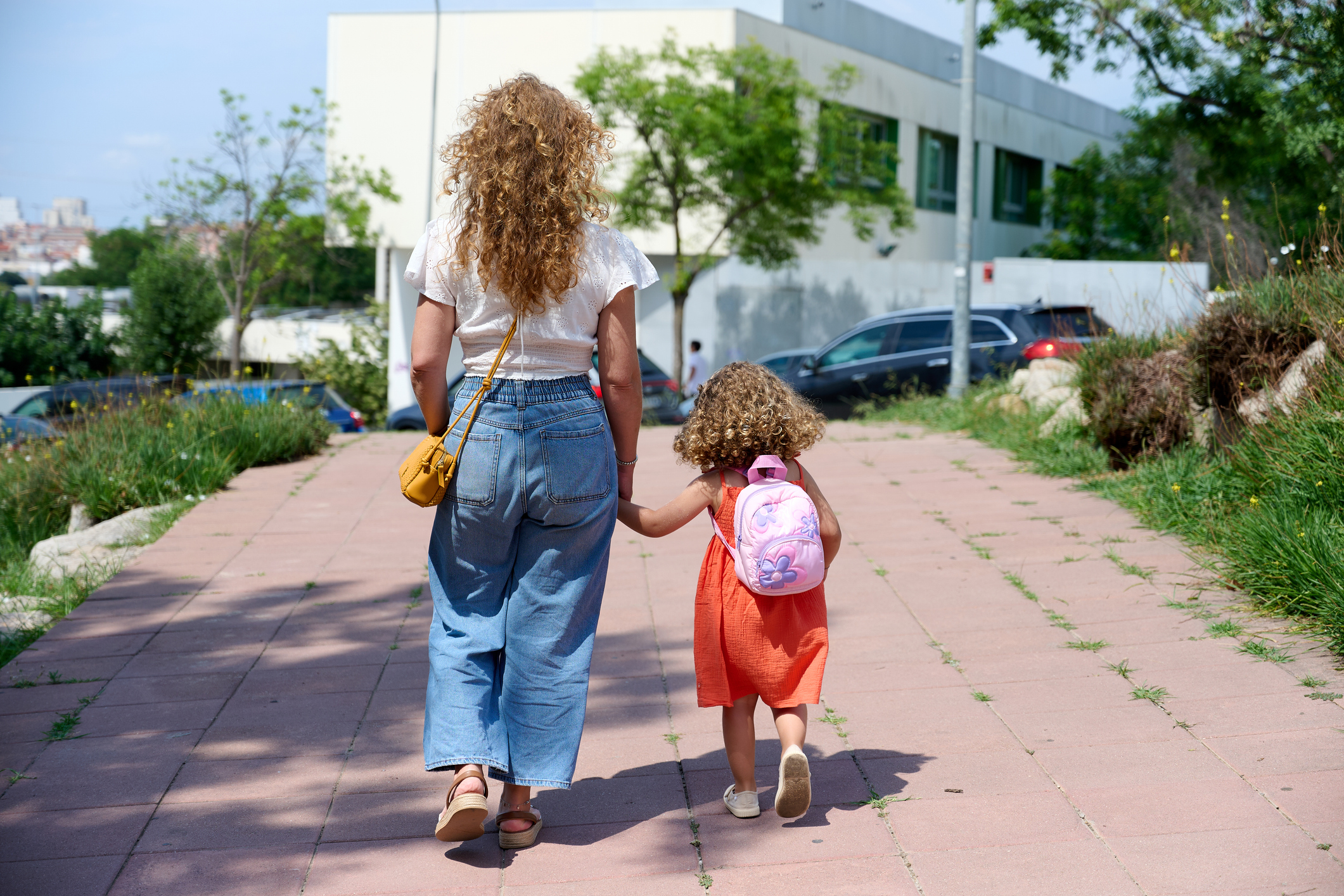 Mother walking daughter to school on a sunny day