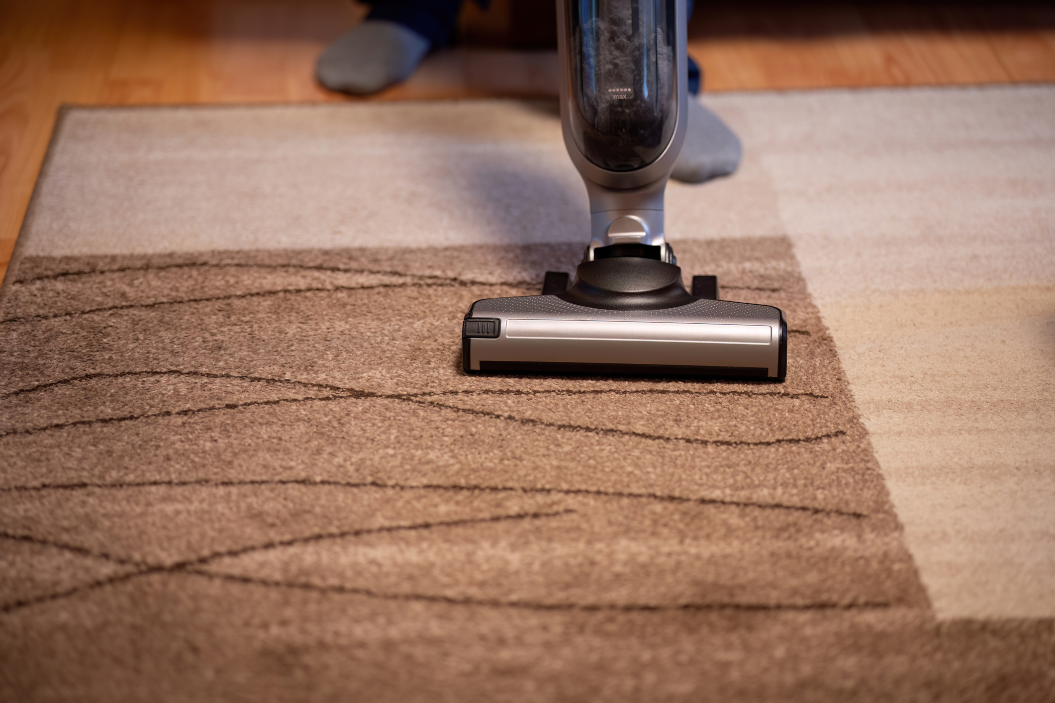 A man is cleaning his home with an electric vacuum cleaner on the carpet.