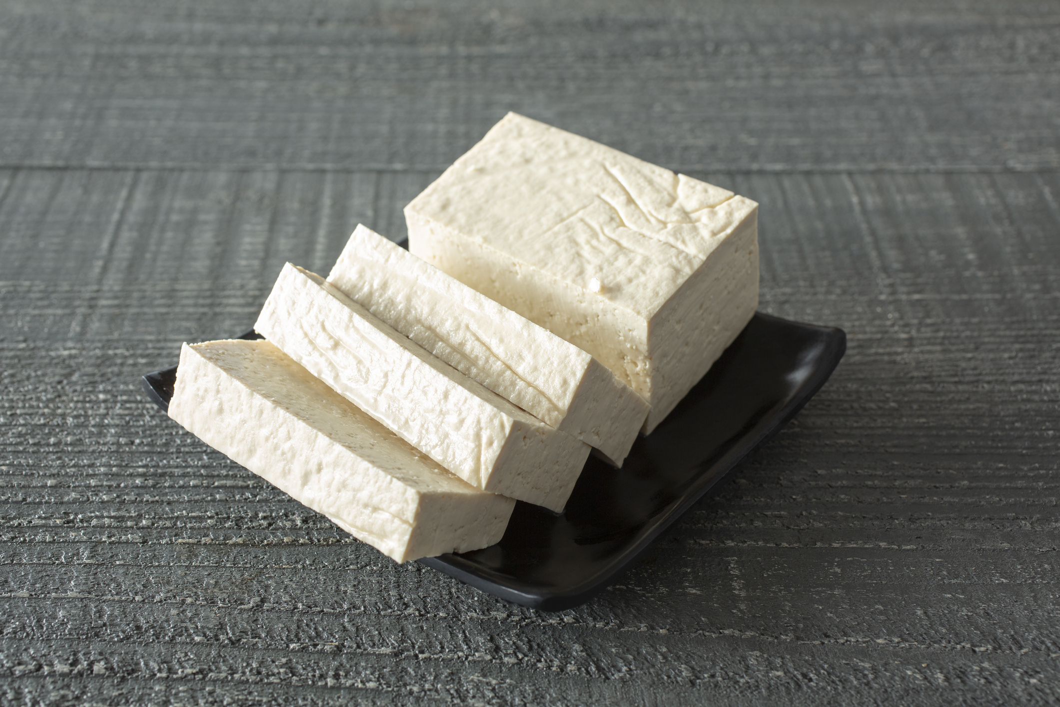 A view of some sliced extra firm tofu pieces on a plate.