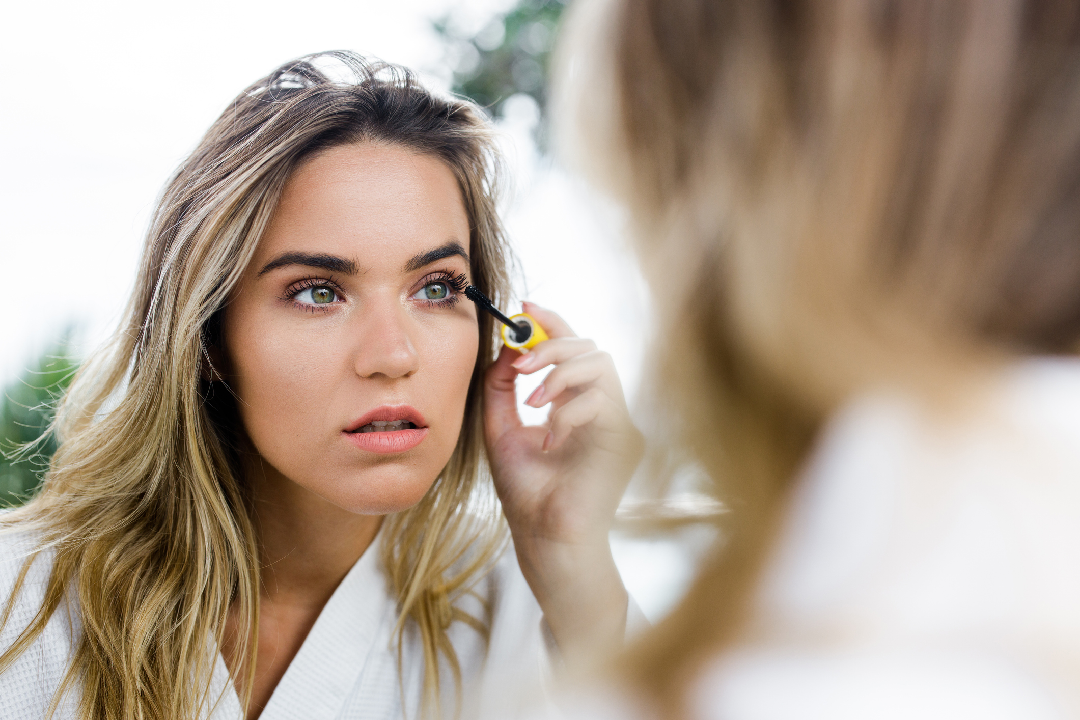 A woman applying makeup in the mirror