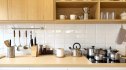 Clean and organized modern kitchen interior with wooden cabinets, white tiled backsplash, and stainless steel appliances. Minimalist Scandinavian style, cozy home cooking space. Bright and inviting.
