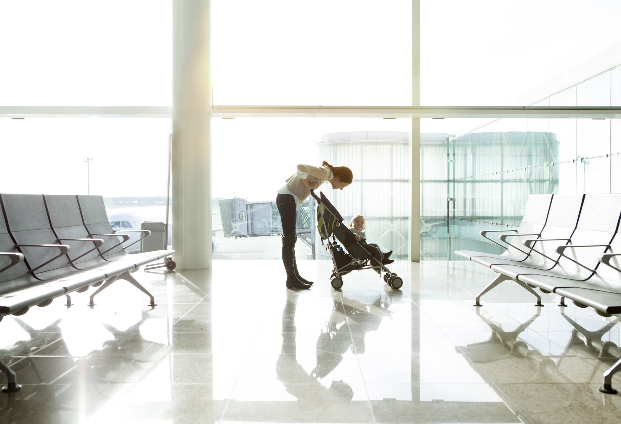 Mother with baby in a travel stroller at the airport.