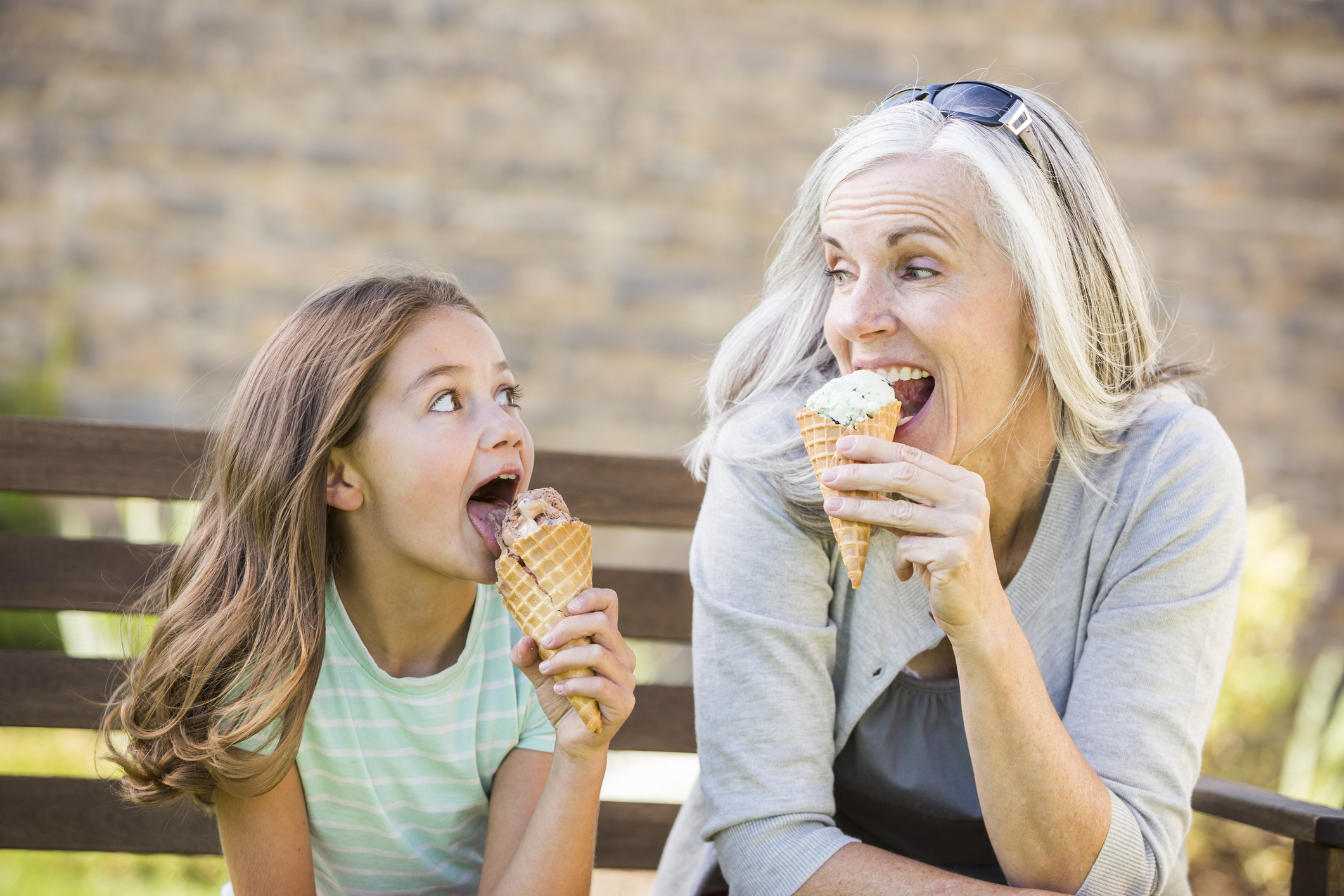 A grandmother and her granddaughter eating ice cream cones.
