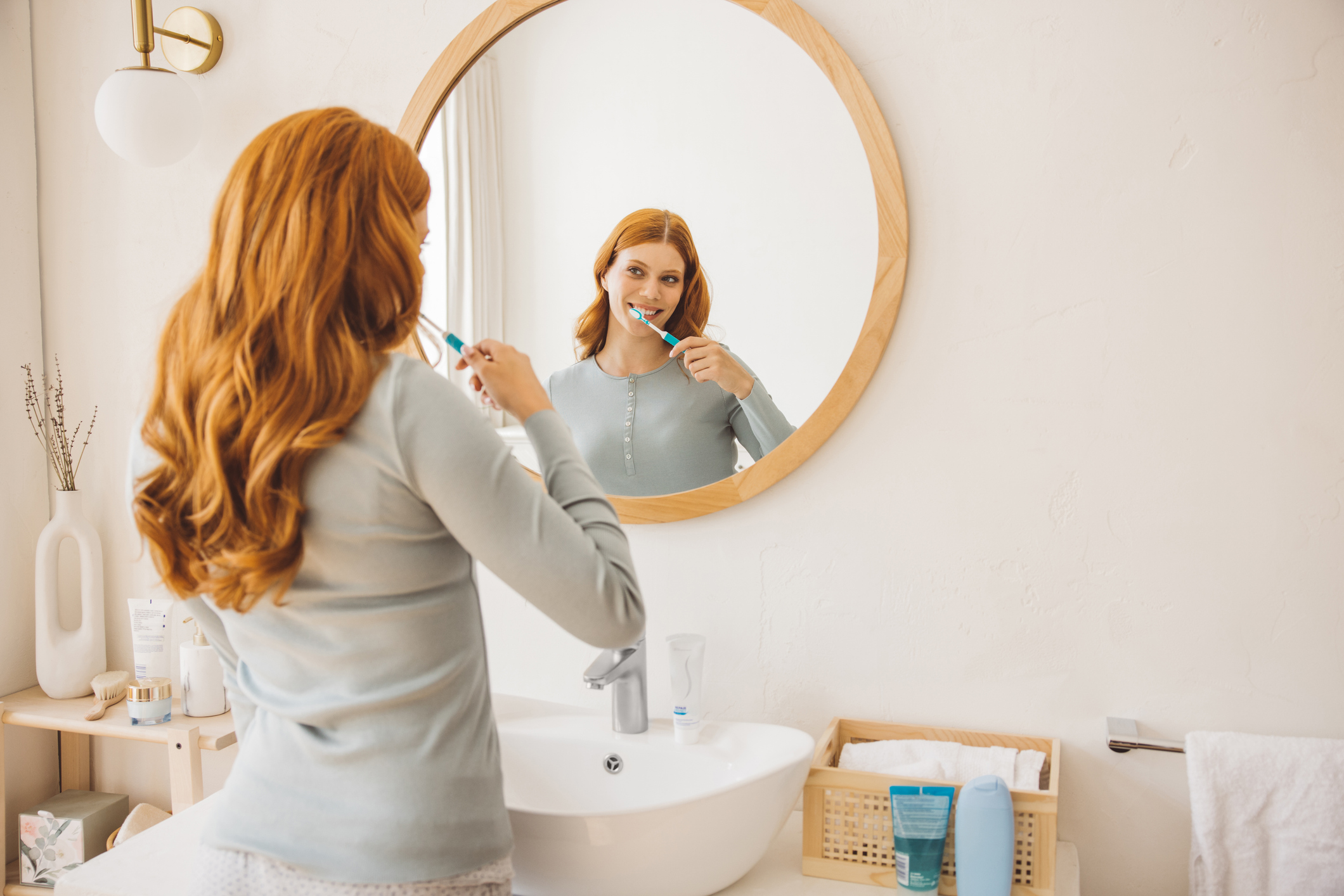 Young woman at bathroom brushing teeth with toothpaste.