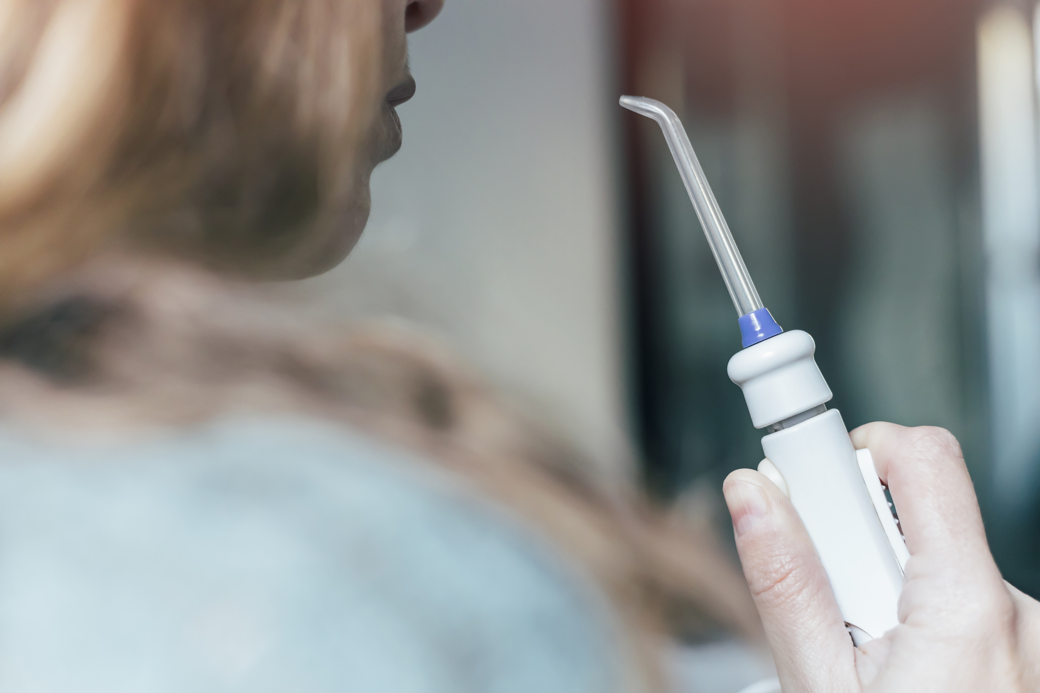 Close up of woman holding oral irrigator dental floss in bathroom