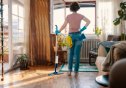A woman with cleaning products, mopping the floor of her home.