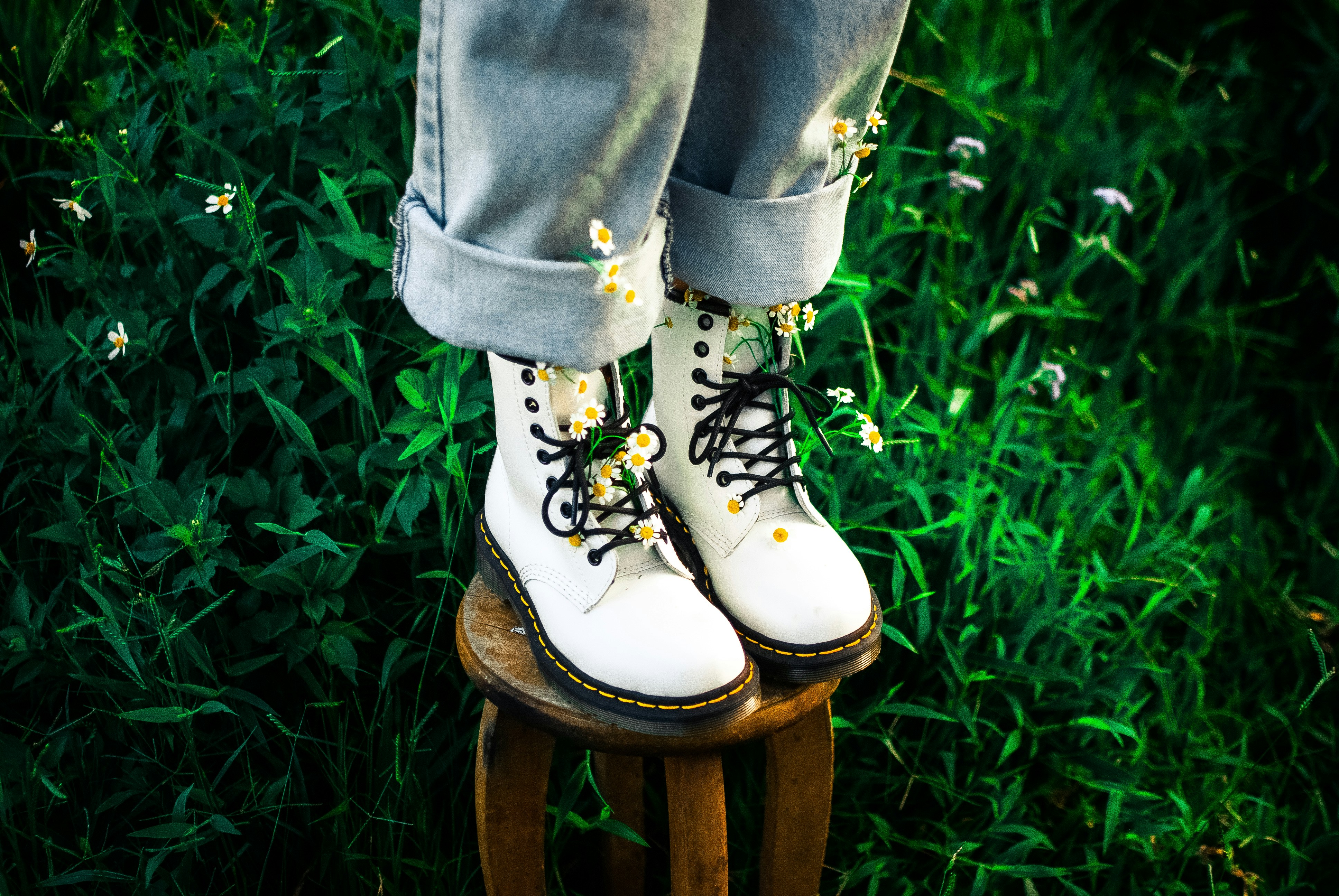 A pair of black and white boots with greenery in the background.