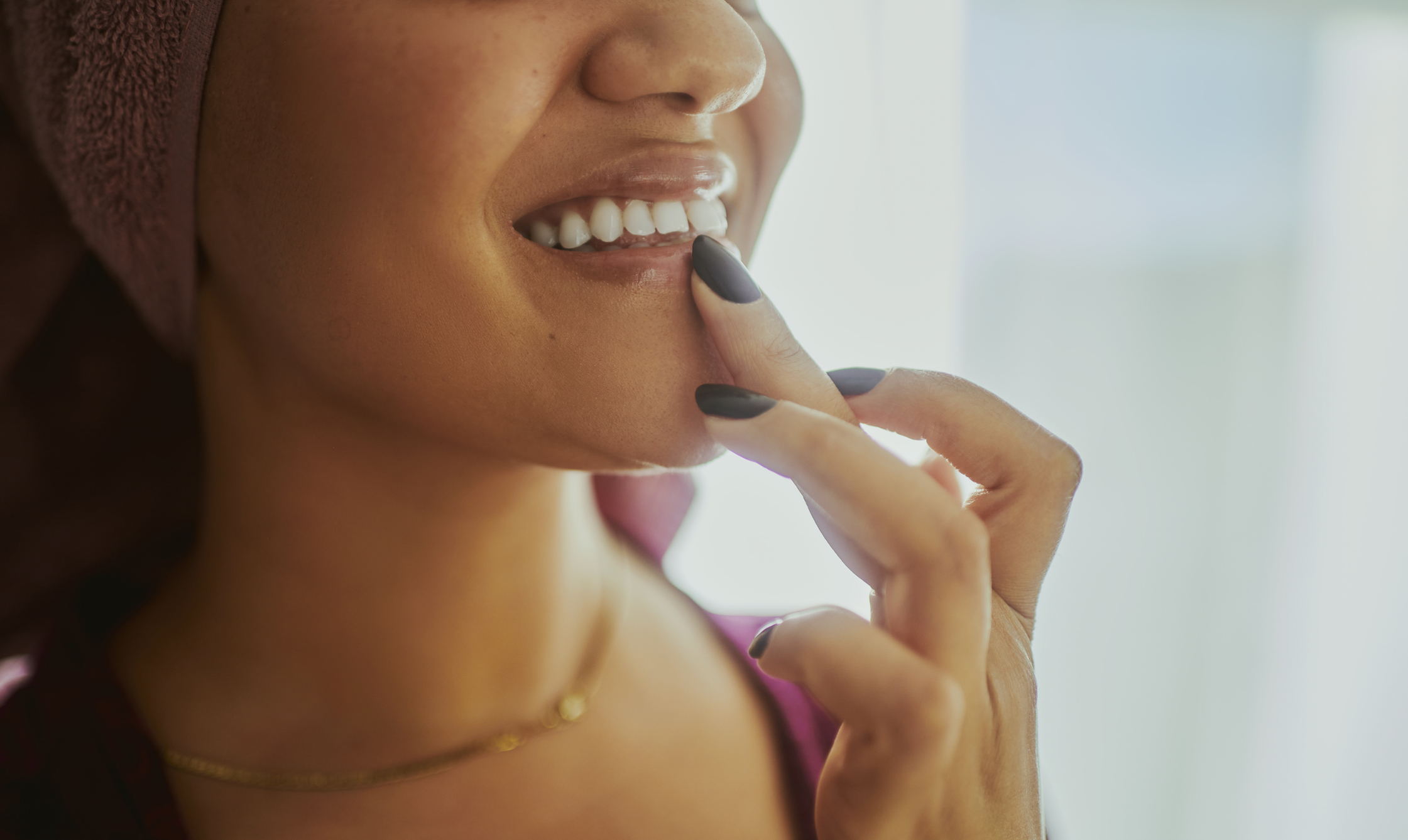 A close-up shot of a woman applying lip balm during her daily skin care routine. Stock photo with copy space