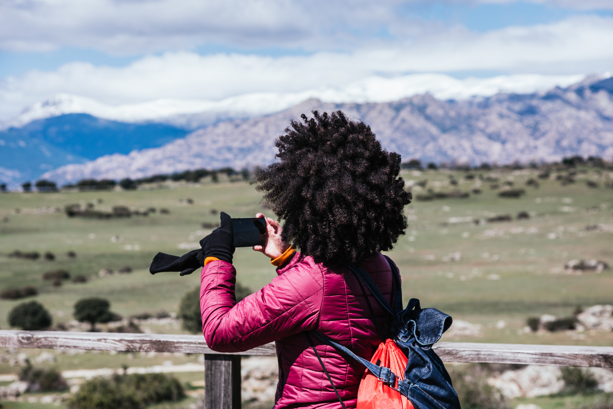 Young woman taking a picture with her mobile of a mountainous landscape