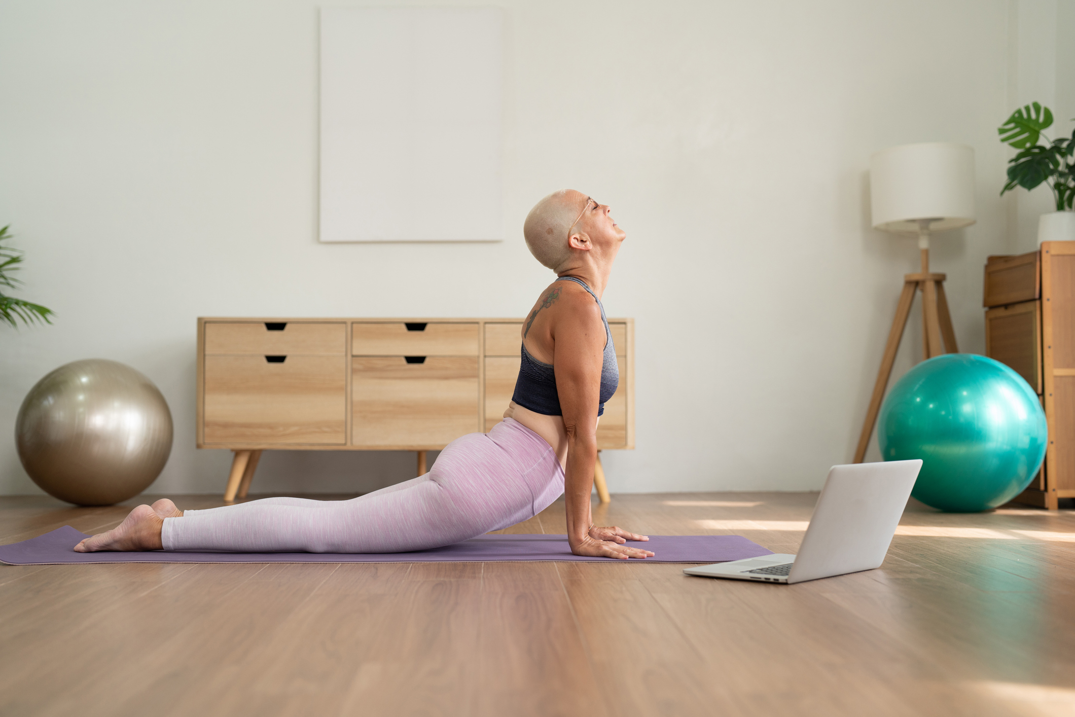 Mature woman enjoying practice yoga exercise through online class doing upward facing dog pose, convenience lifestyle for healthcare workout at home