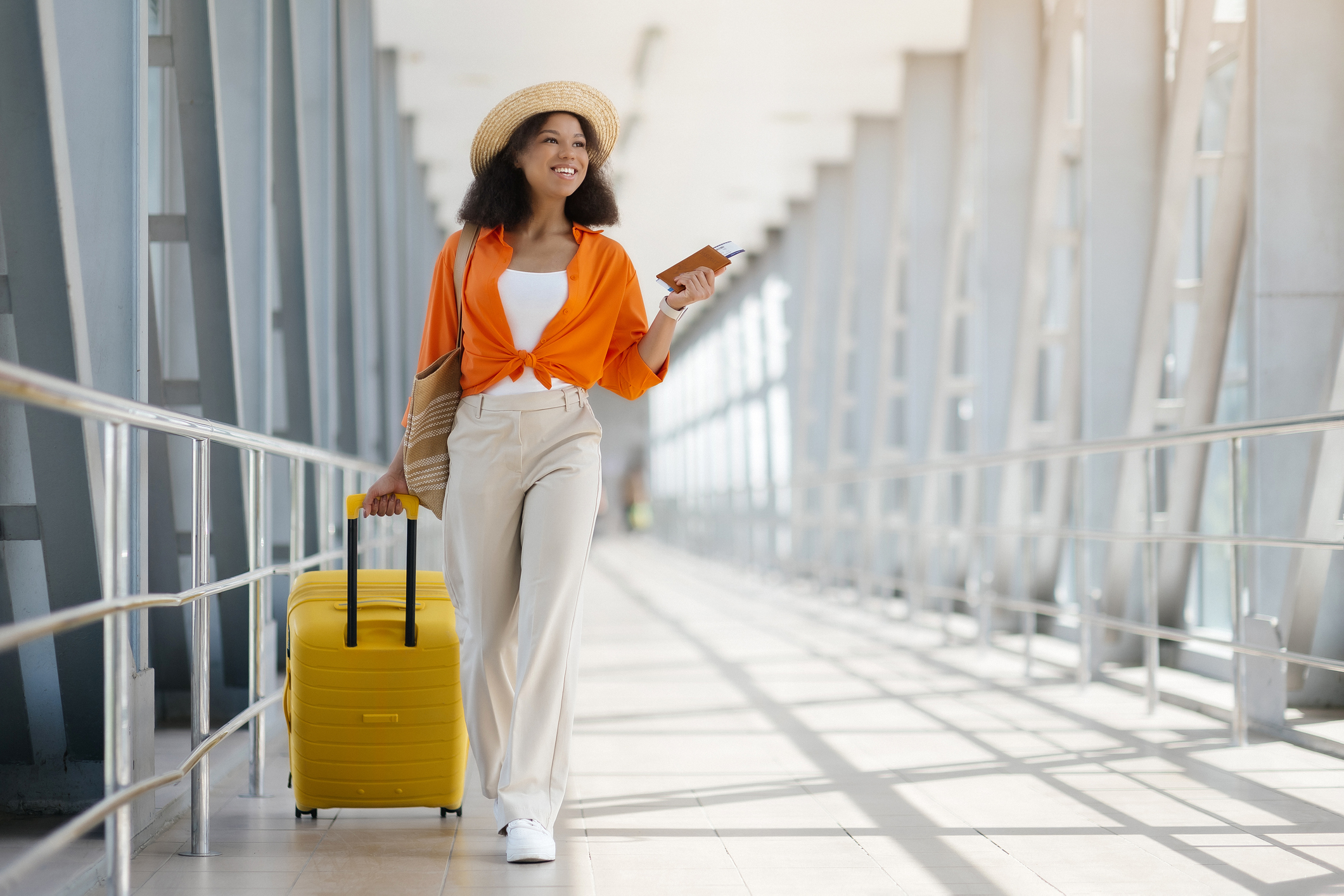 Fashionable woman walking through an airport terminal with her suitcase in tow.