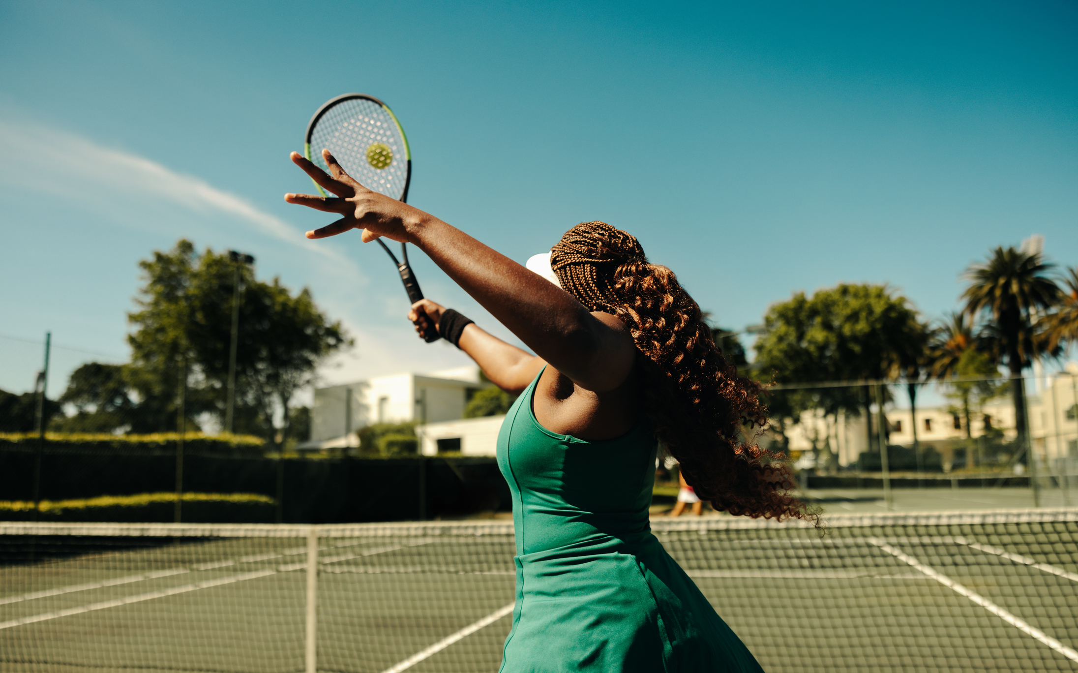 Female tennis player hitting a volley on a hardcourt on a sunny day
