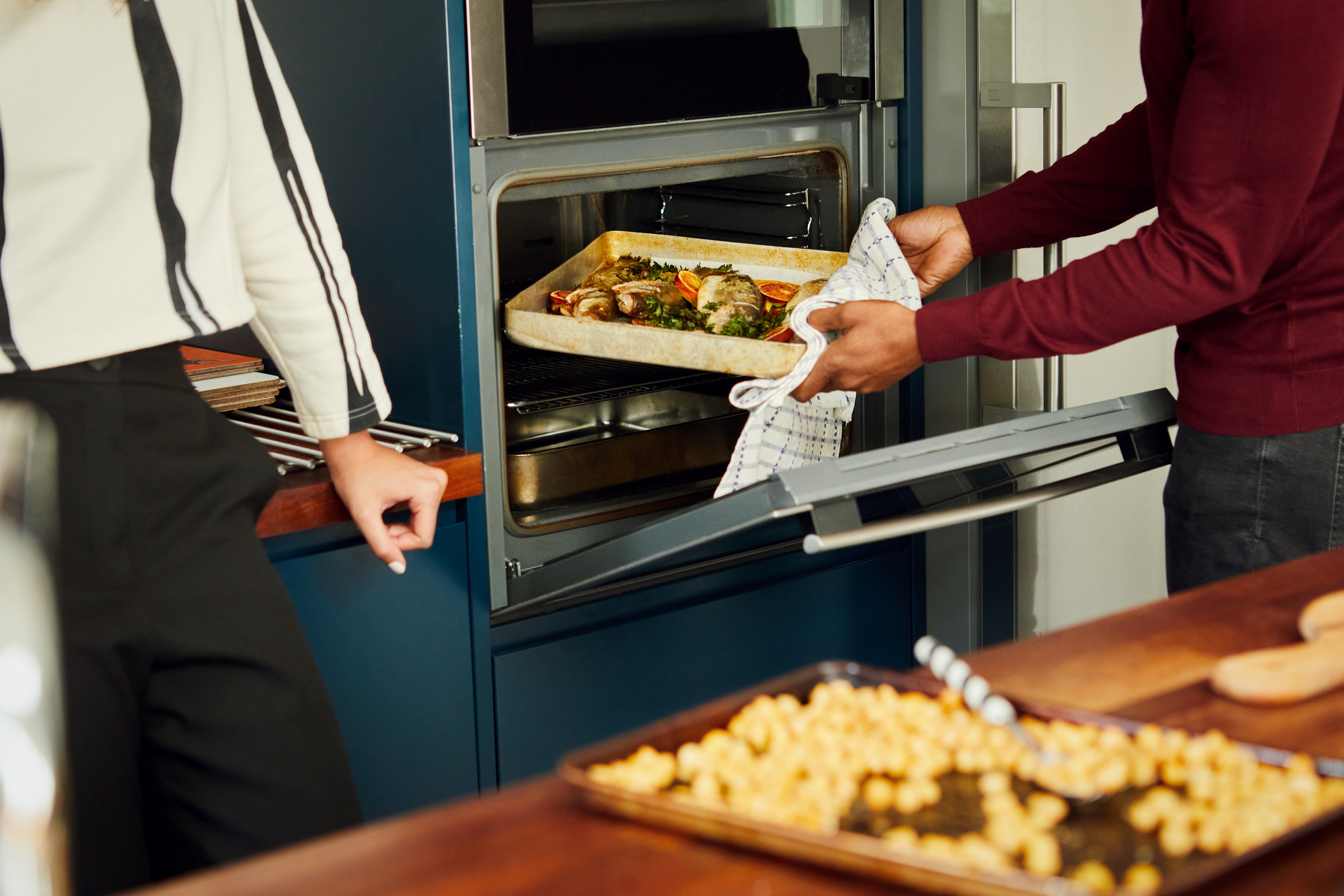A family preparing food in the kitchen; putting a dish in the oven