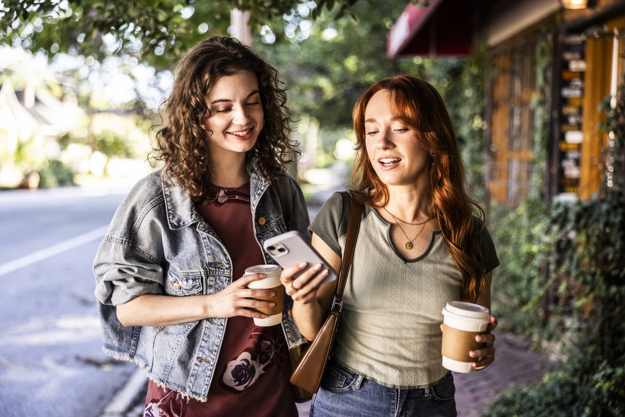 Young females walking down city street and using smartphone