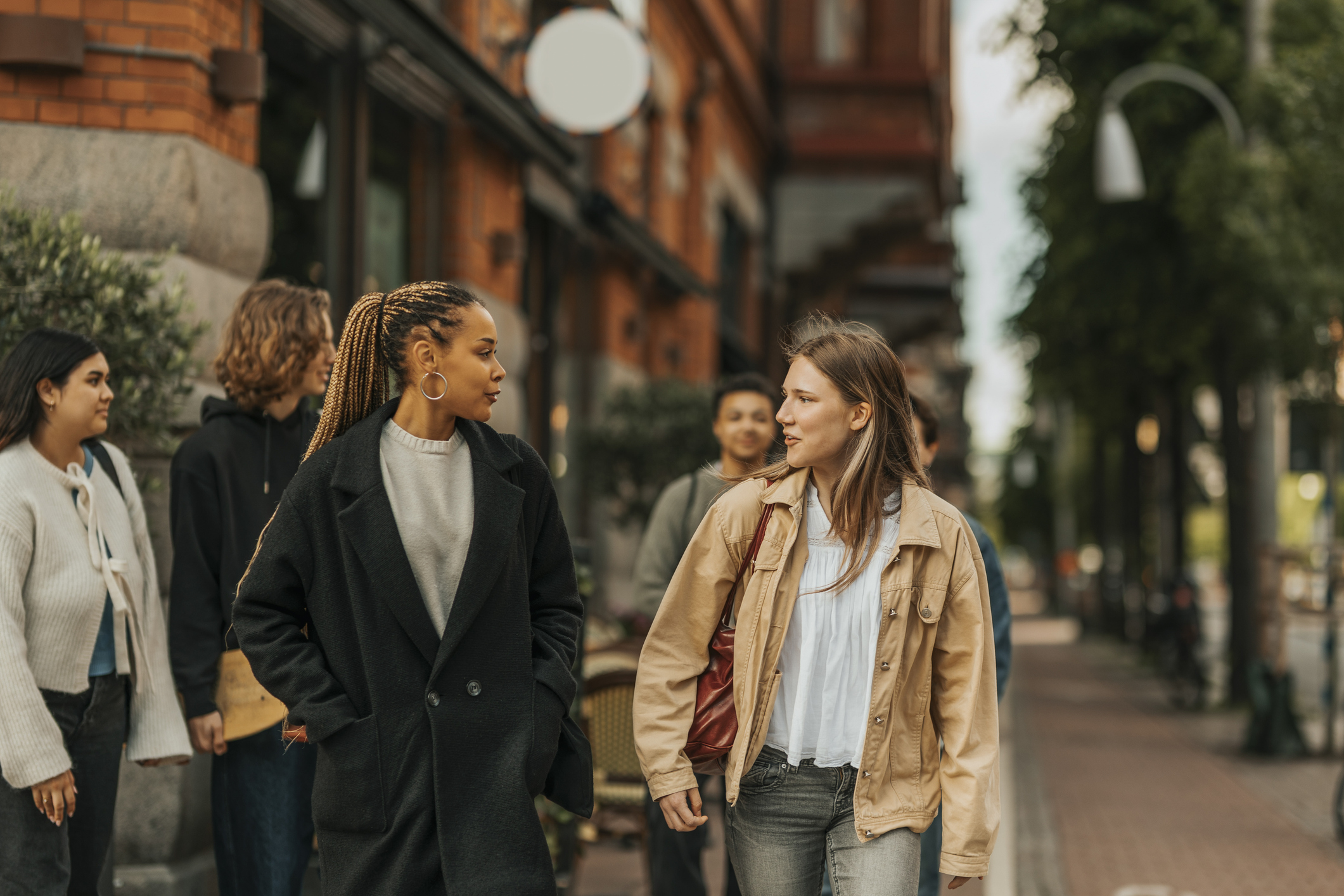 Young woman talking with female friend while walking at city street