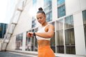 Woman in athletic gear taking a break outside to check her smartwatch.