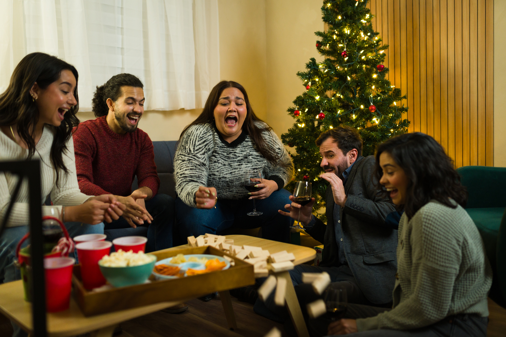 Seasonal party indoors with a group of friends enjoying drinks and snacks while playing a fun board game together
