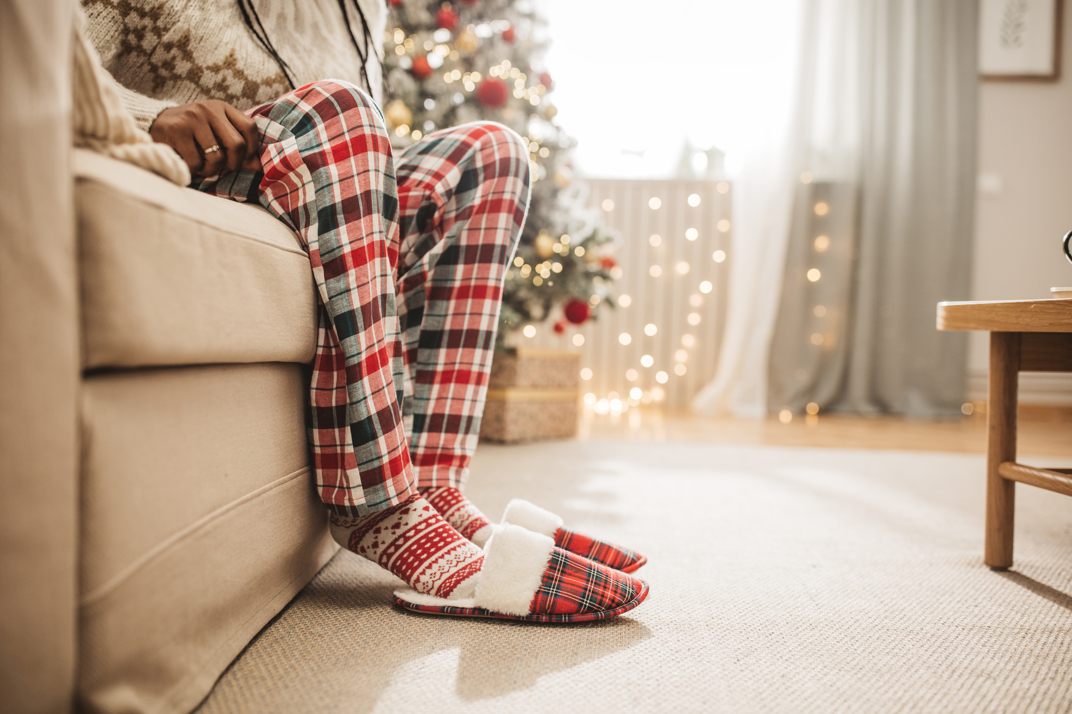 Young women sitting at the end of the sofa in home slippers and pajamas.