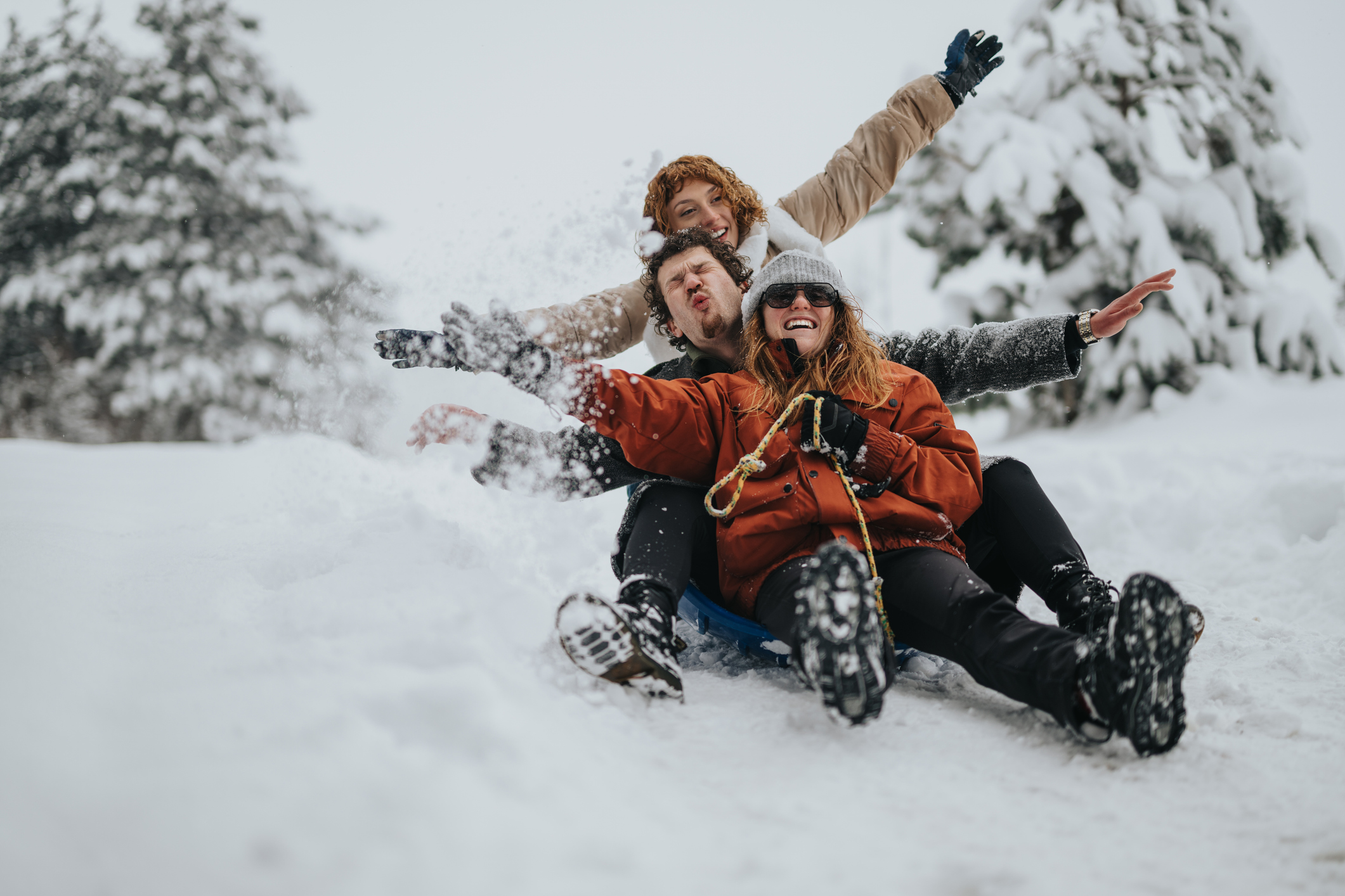 Joyful friends sledding together in a snowy hill, showcasing winter fun and happiness.