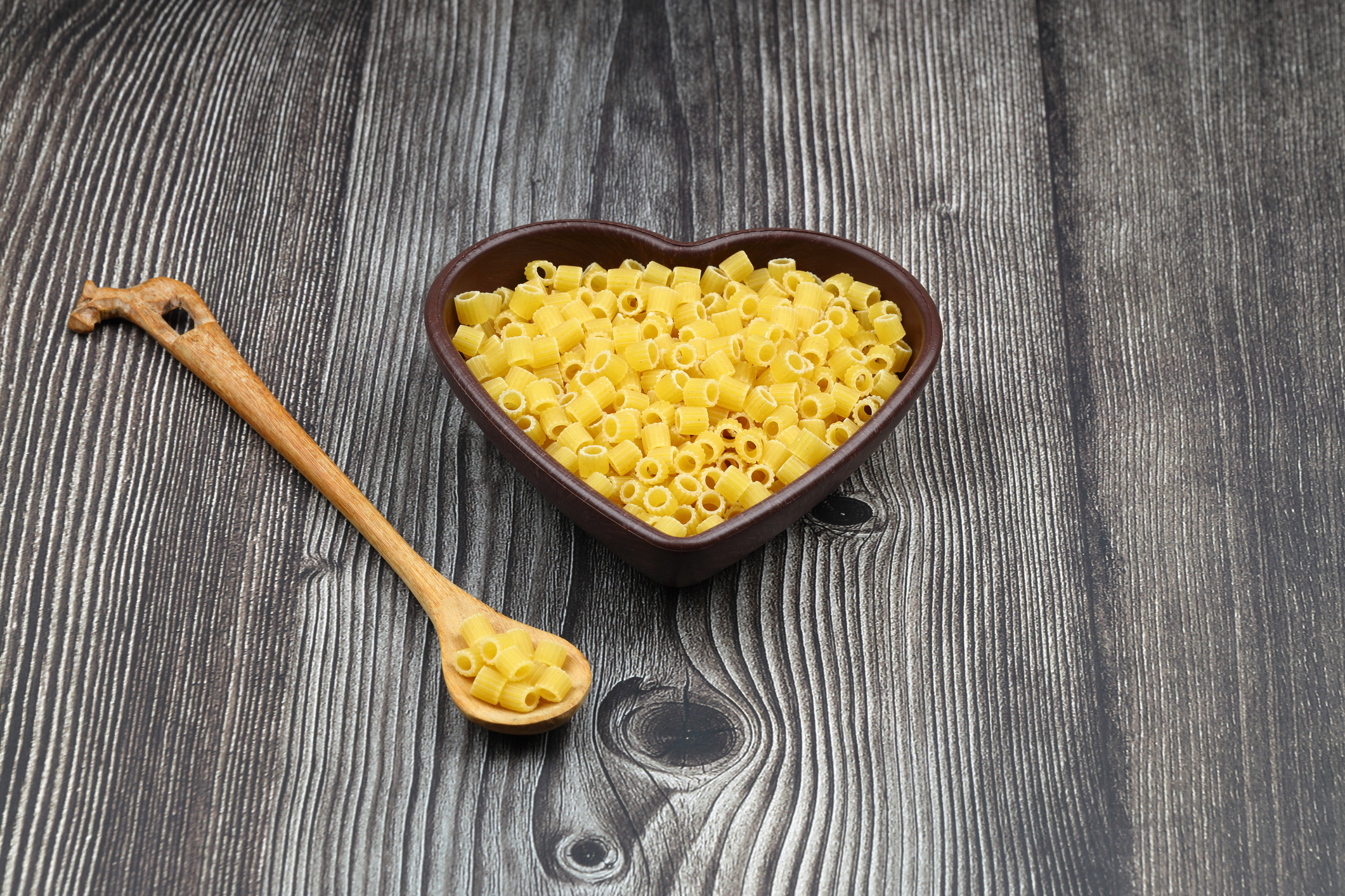 Pasta in the shape of a heart on a wooden background