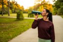 Young female athlete drinking water while resting in nature.