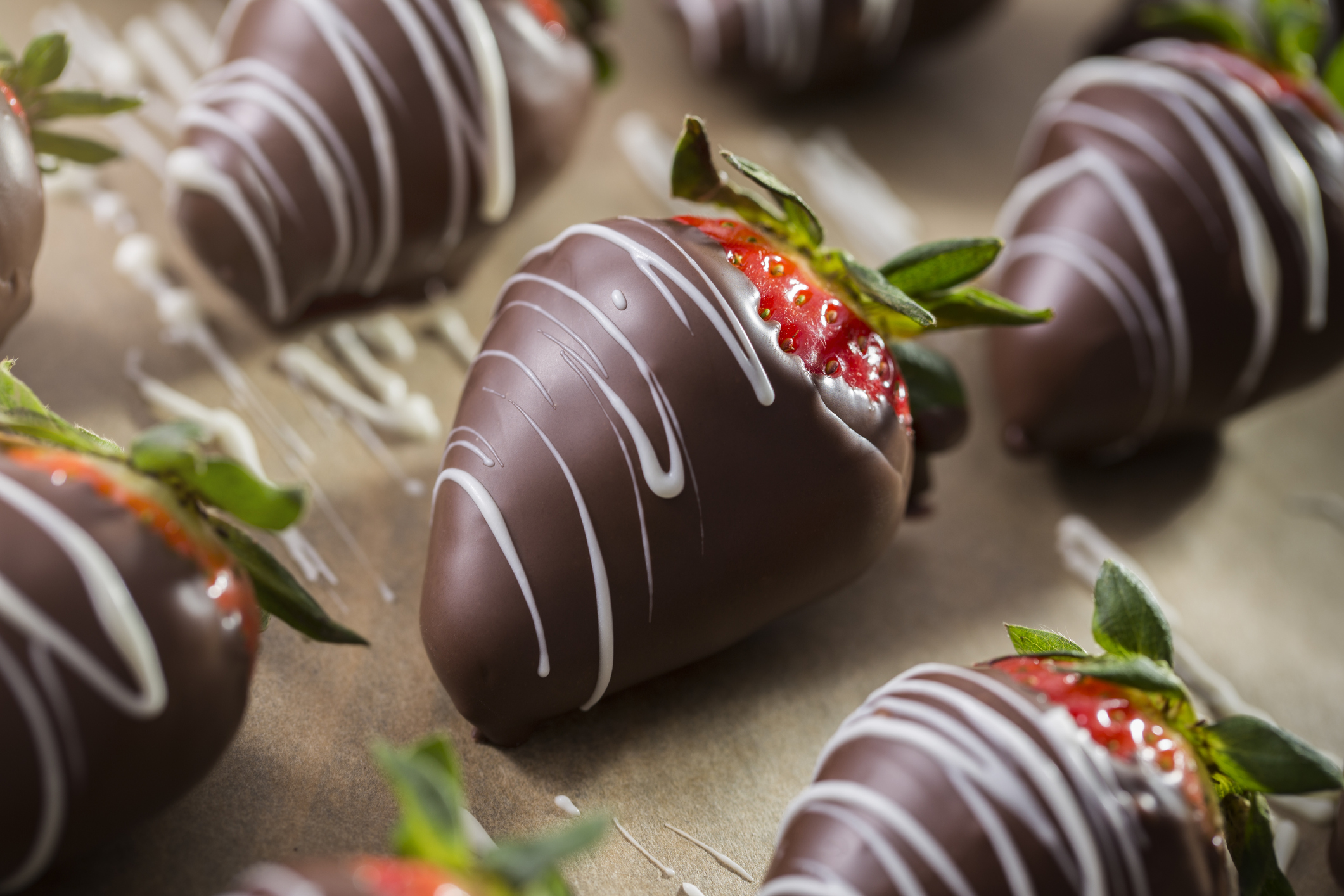 Chocolate covered strawberries with milk chocolate and white chocolate on parchment paper.