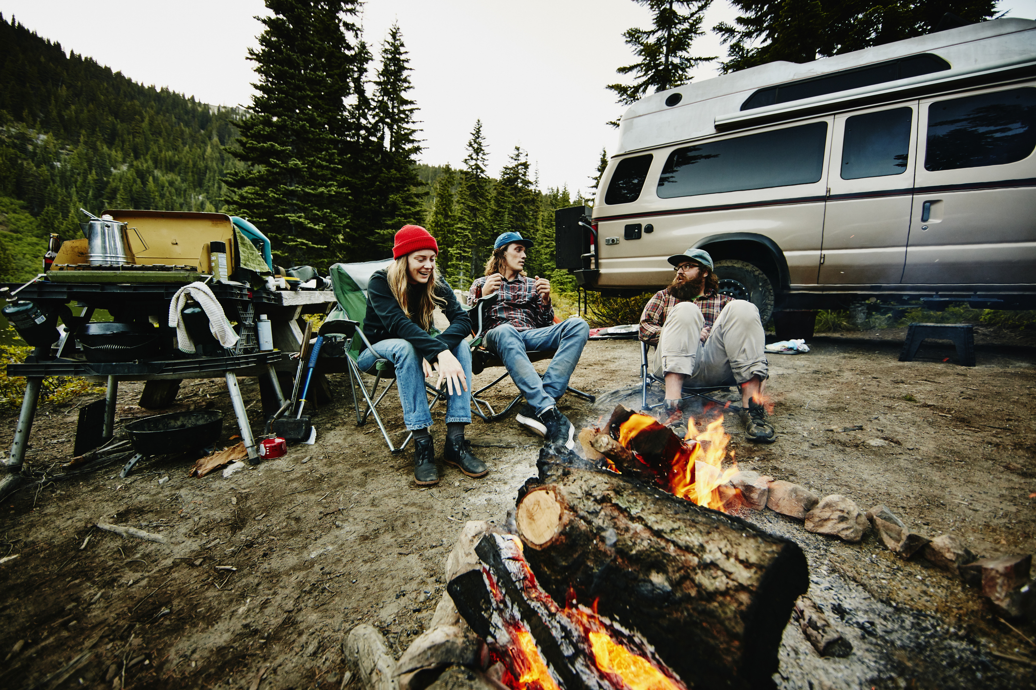 Smiling group of friends sitting near fire while camping