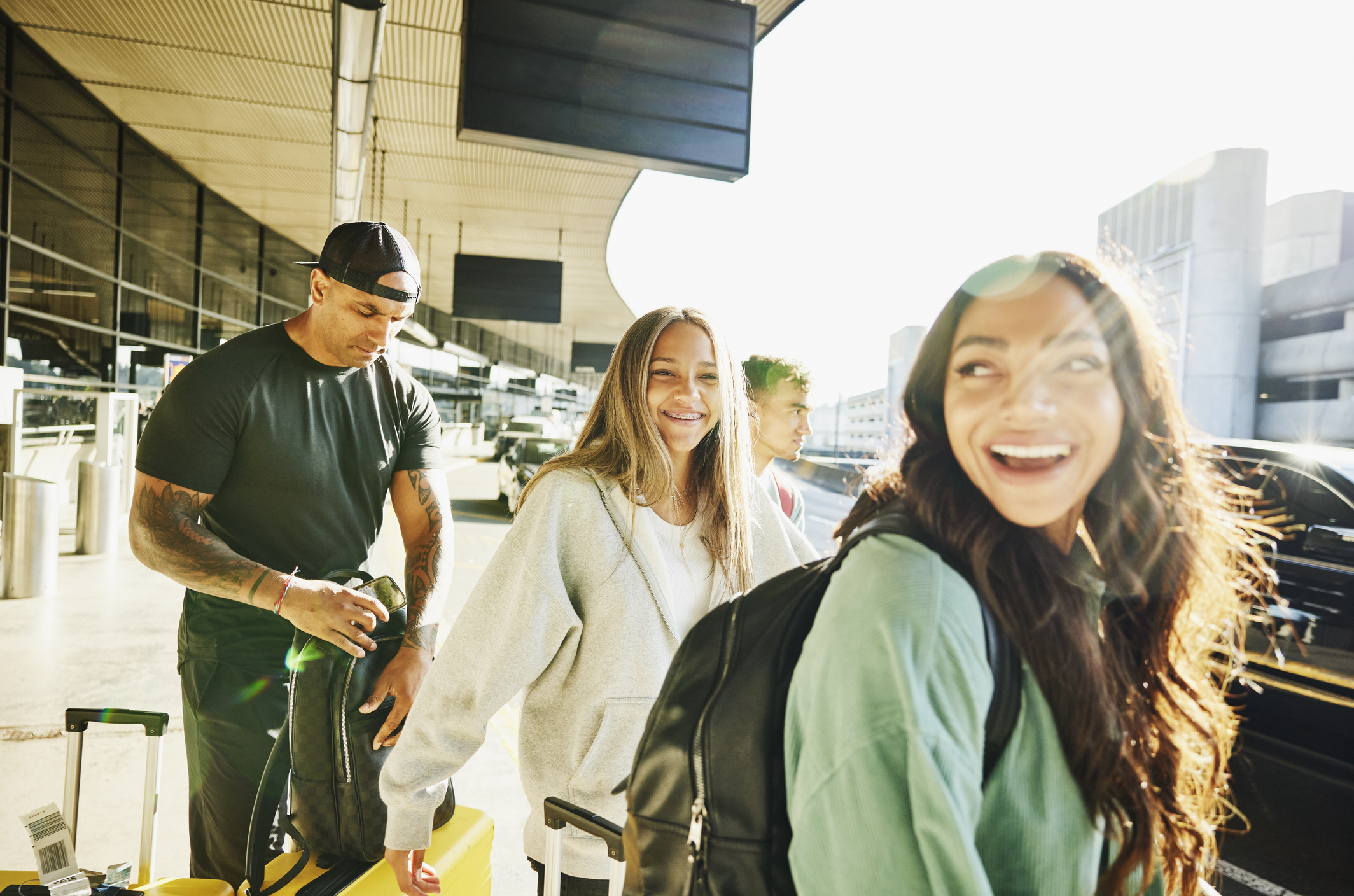 Medium shot of smiling family arriving curbside at airport before departing on vacation