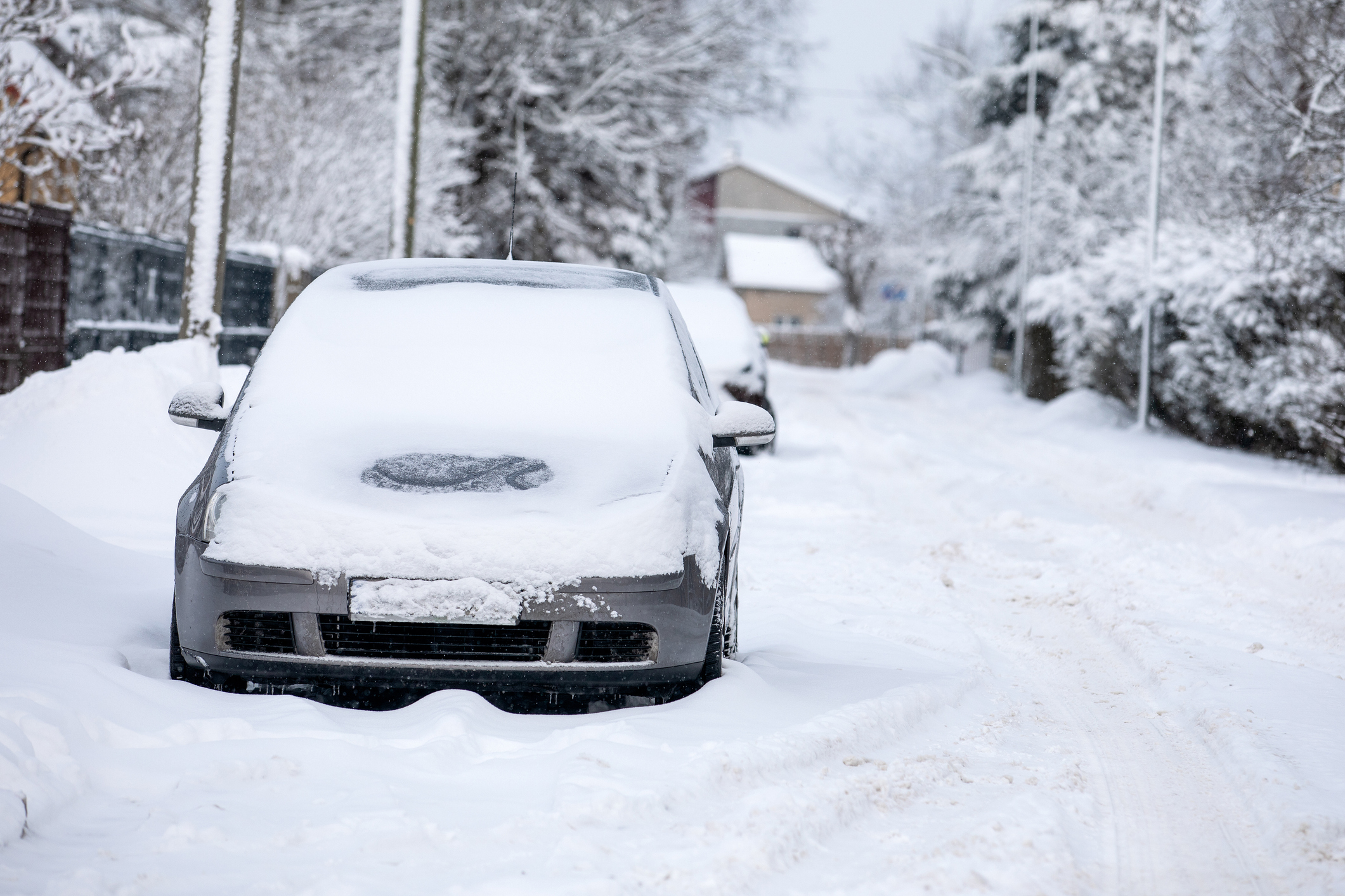 Snow-covered car in the street covered with a thick layer of snow on a winter day.