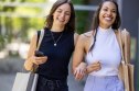 Happy young women with shopping bags outdoor. Smiling female friends walking together on city street with shopping bags.