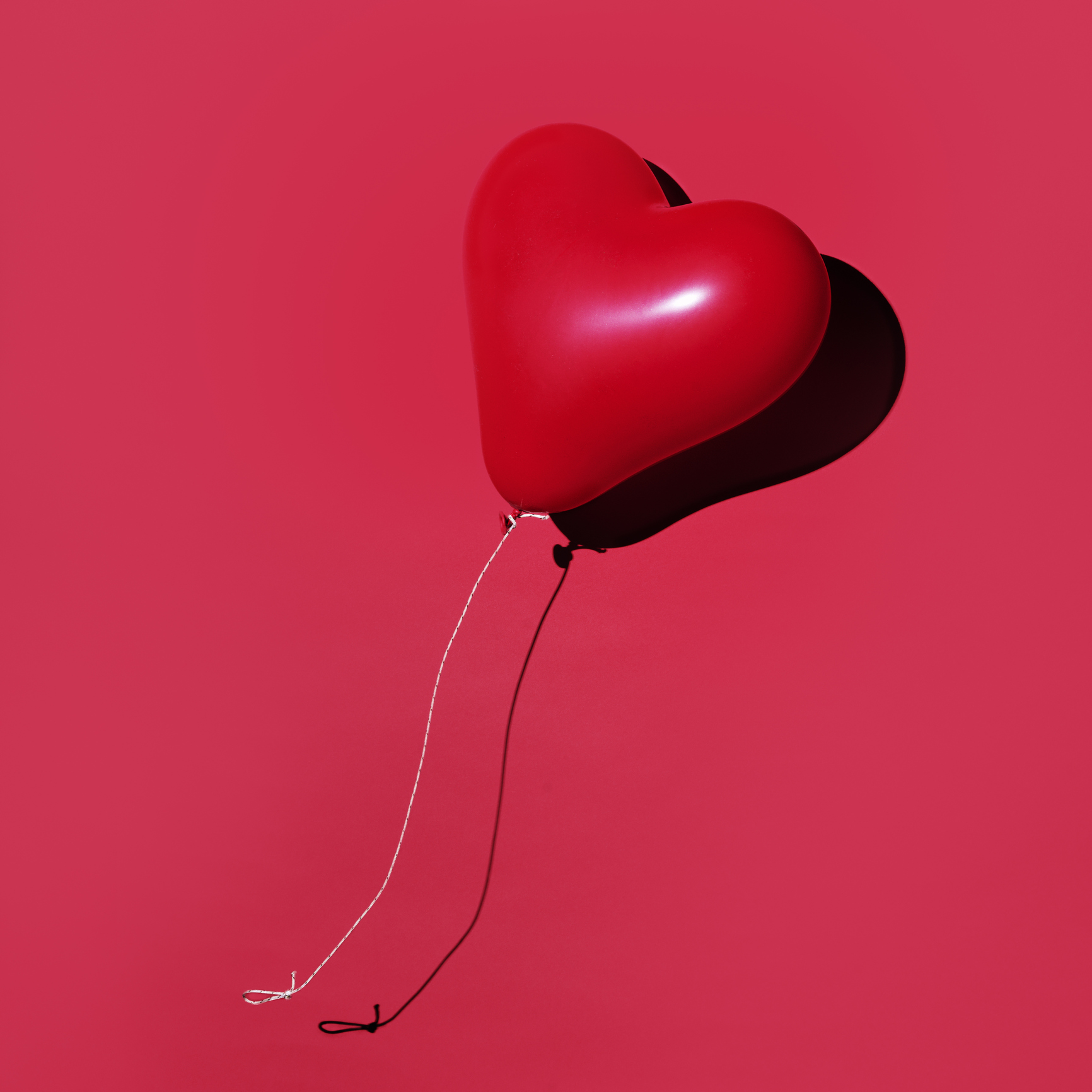 red balloon levitated , floating, photographed on red backdrop