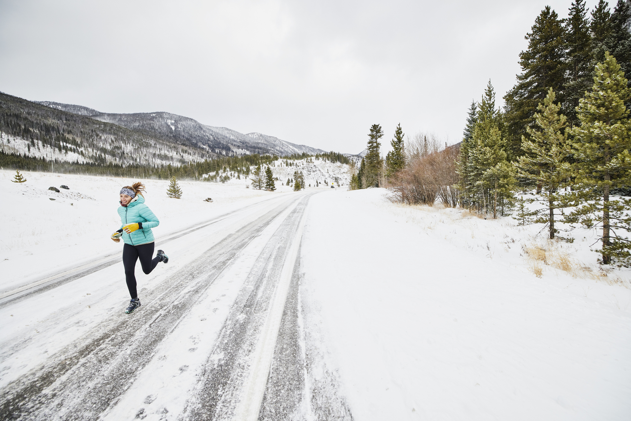Smiling woman on winter run on snowy road