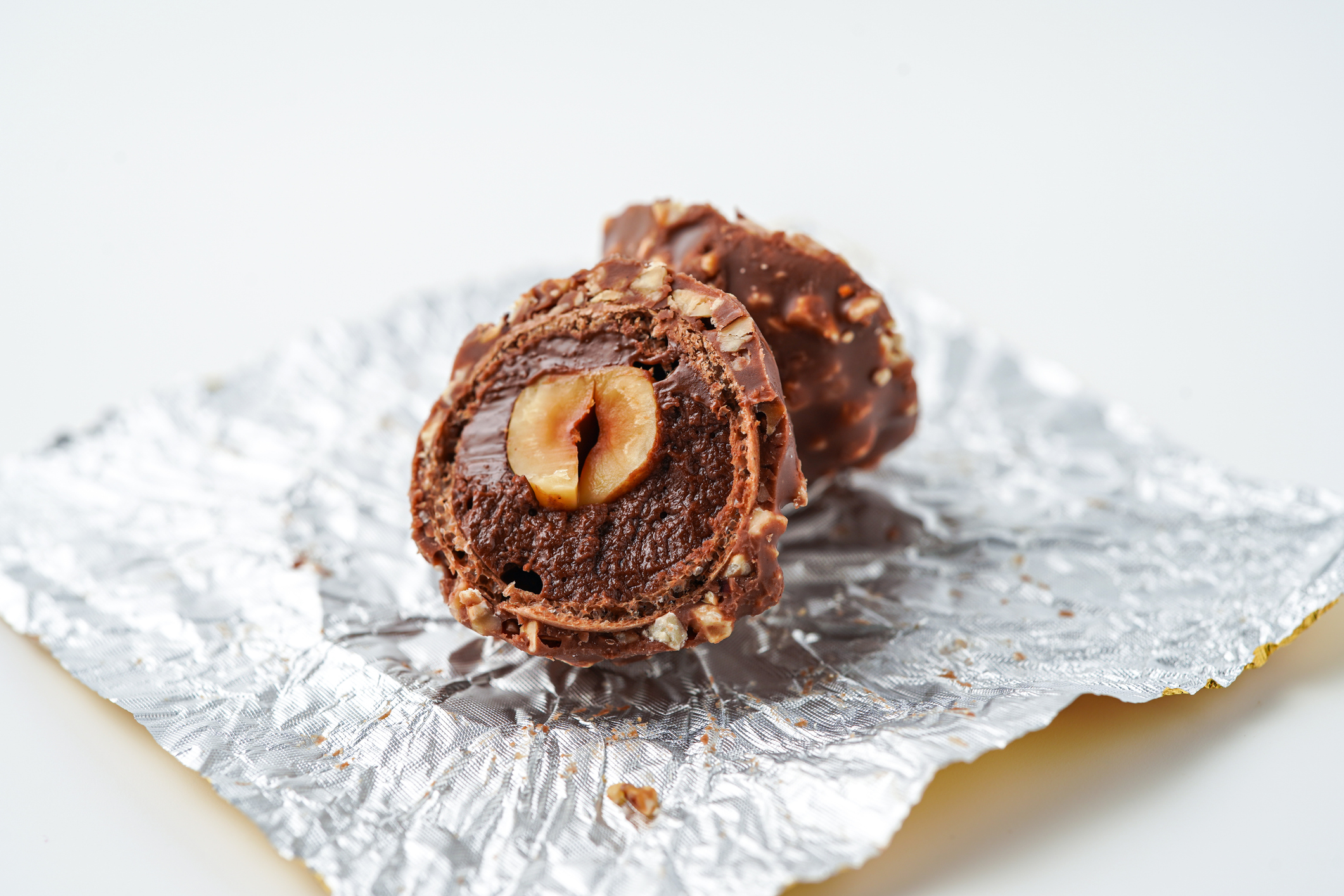 Sweet chocolate balls is made. Chocolate candy in gold wrapper on white background