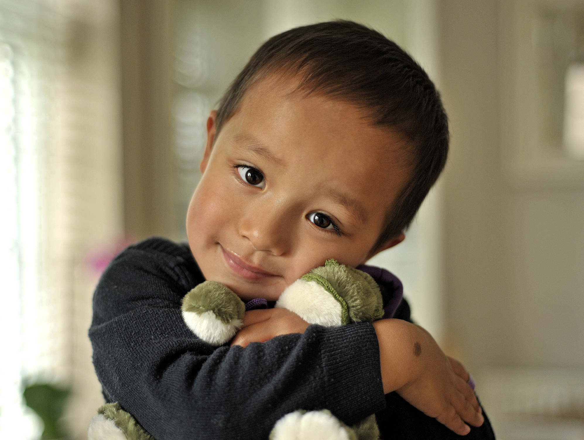 Boy cuddling his soft toy in natural light.