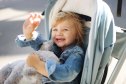 Portrait of a happy baby girl hugging her teddy in her baby-buggy