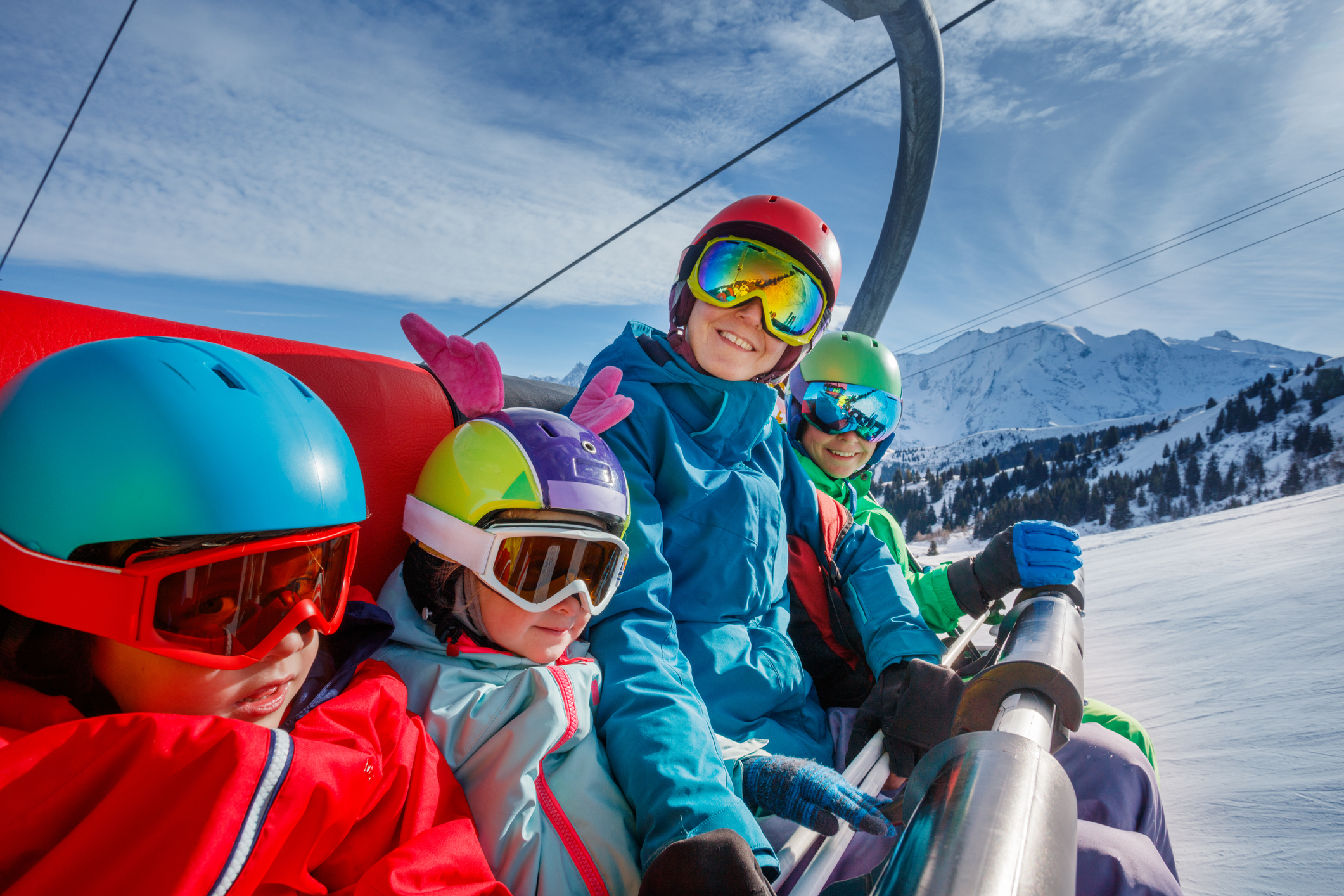 Amidst the beautiful alpine landscape, a family takes a break on a ski lift, their colorful outfits standing out against the pristine snow
