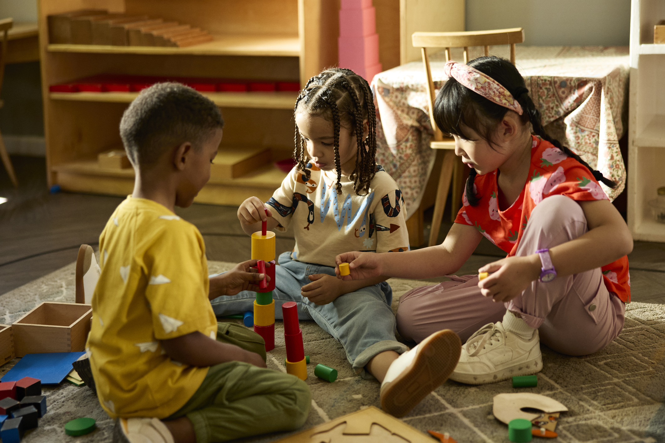 Male and female friends playing together with toy blocks in classroom