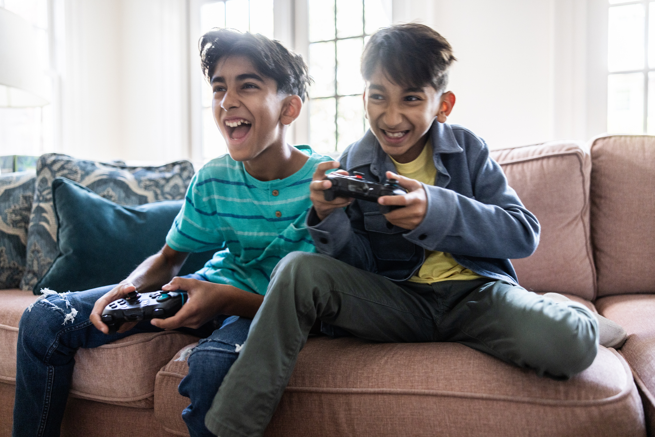 Young boys playing video games on sofa at home