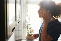 Mature female nurse touching face while looking in mirror at bathroom
