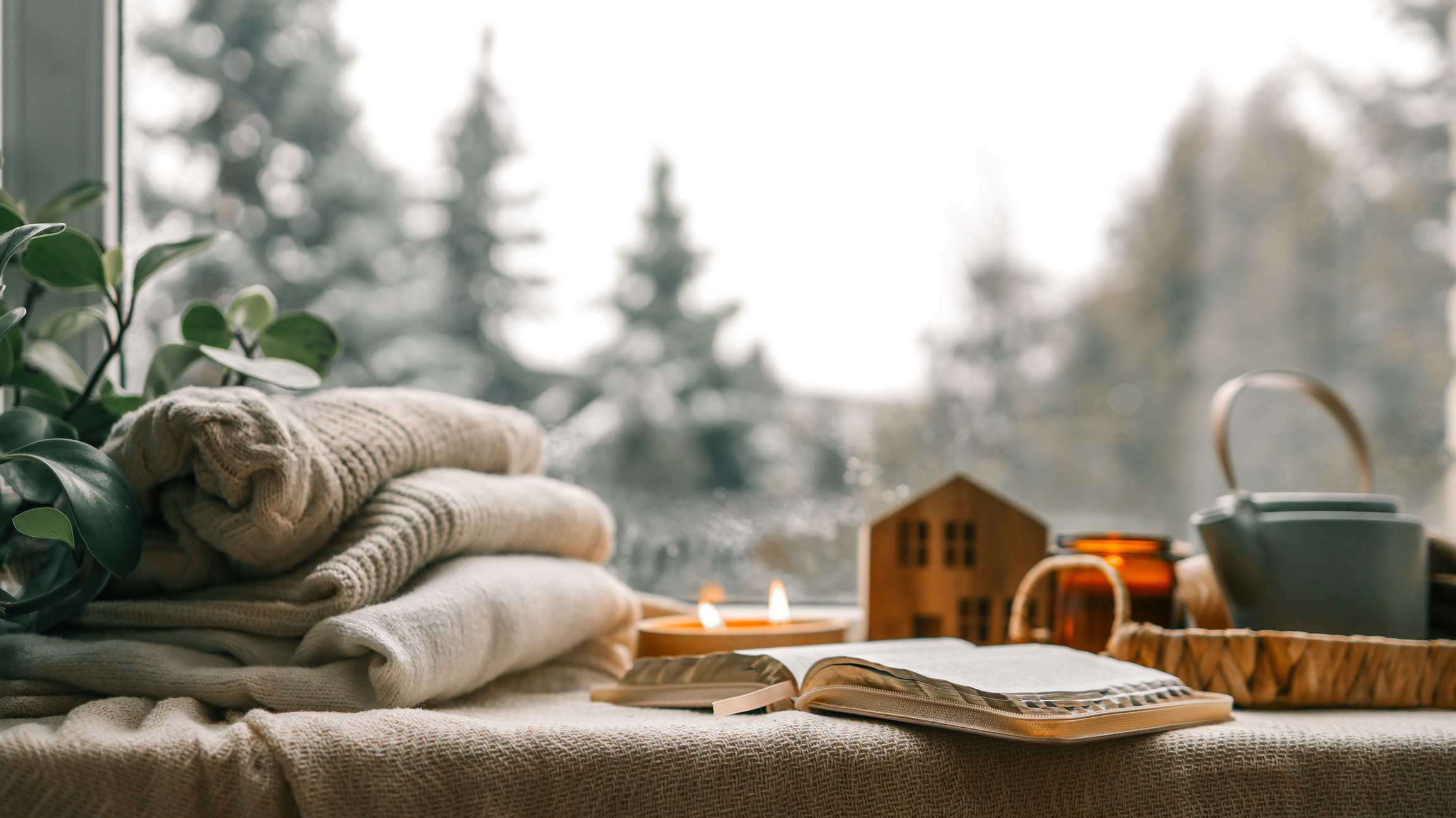 Cozy winter photo, stack of sweaters, open book, tea and candle.