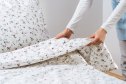 Concept of hotel service, household and chores. Close up view of woman makes bed in her bedroom. Spring cleaning and change of linen. Female hold blanket with a clean duvet cover in a flower pattern