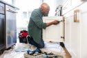 Senior man repairing kitchen cabinet at home