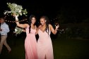 Cheerful young multiracial bridesmaids holding flower bouquets while dancing at wedding reception during night