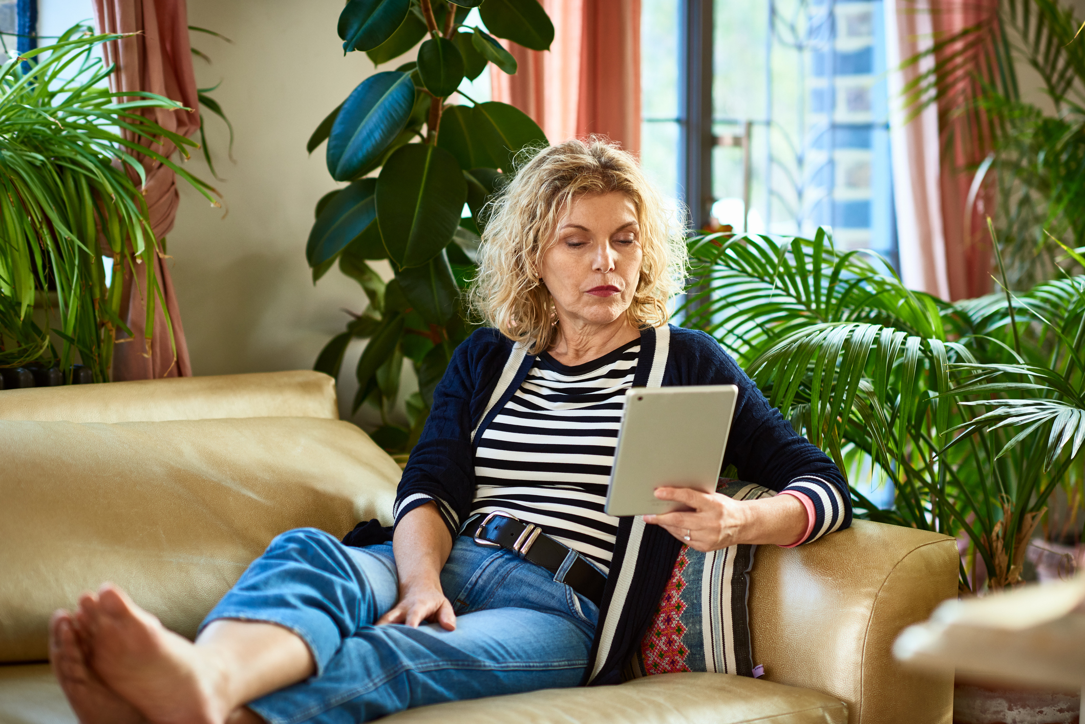 Woman in her 50s with feet up, reading from one of the best e-readers under $100