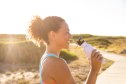Female jogger drinking water while out for a run in nature