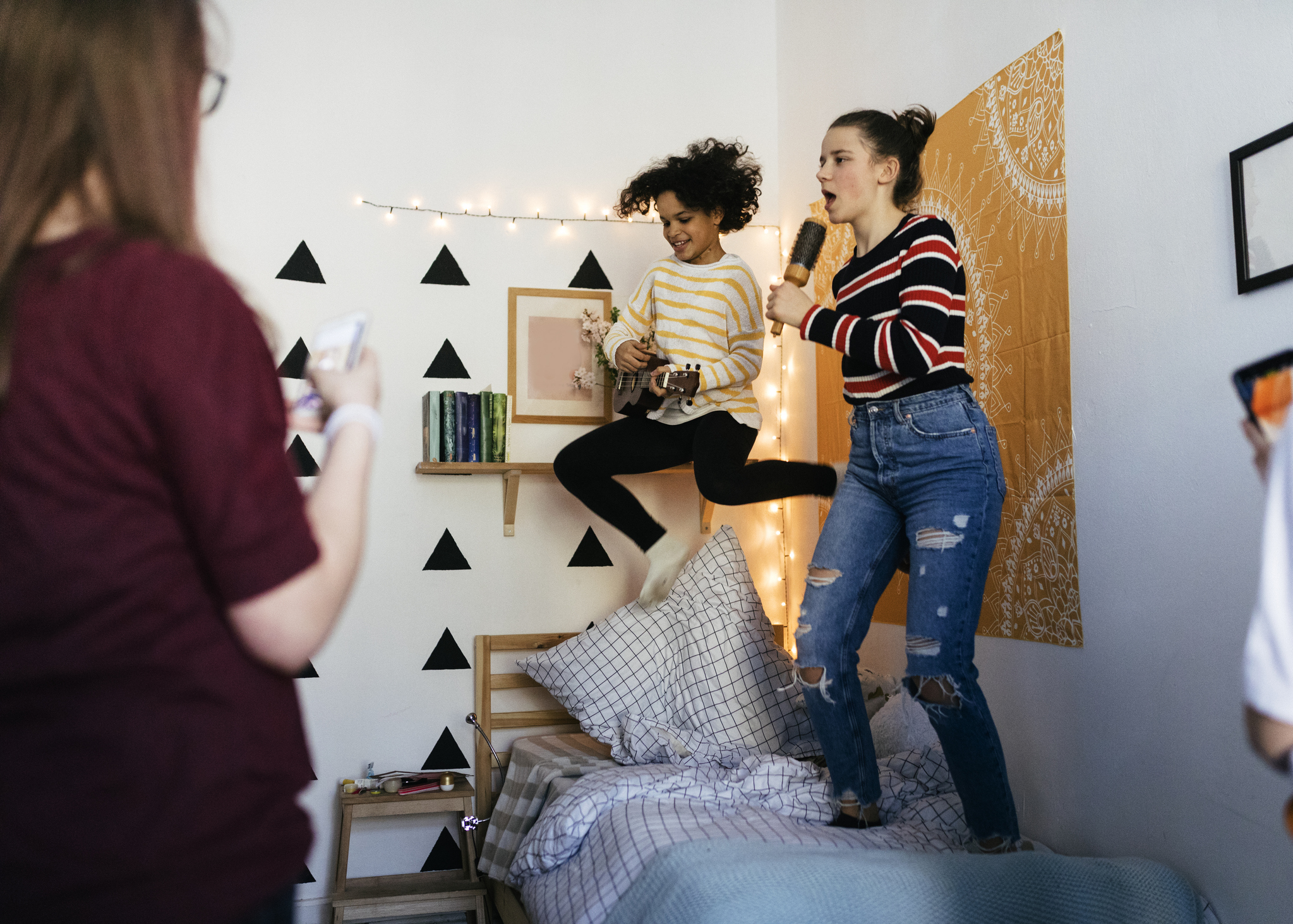 Cheerful girls singing into hairbrushes at slumber party.