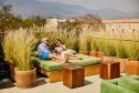 Wide shot smiling senior couple relaxing on rooftop daybed of luxury hotel during vacation to Oaxaca