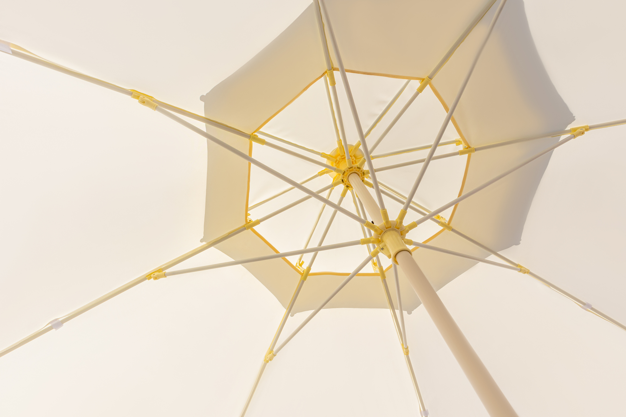 A large open outdoor umbrella of beige color. Umbrella for protection from the bright sun on the beach, cafe, patio, terrace. Realistic photo