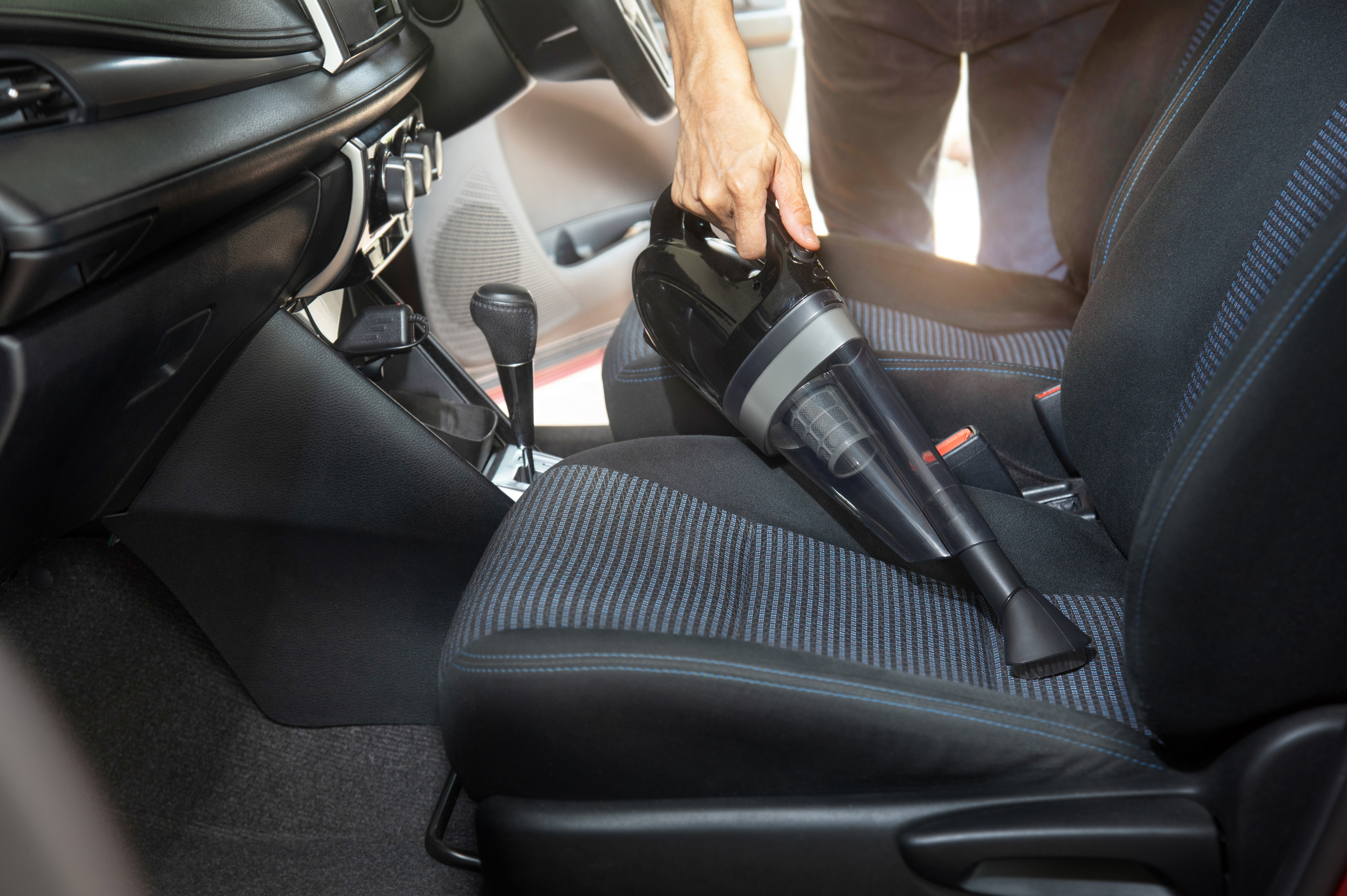 Employee cleaning car with portable vacuum cleaner